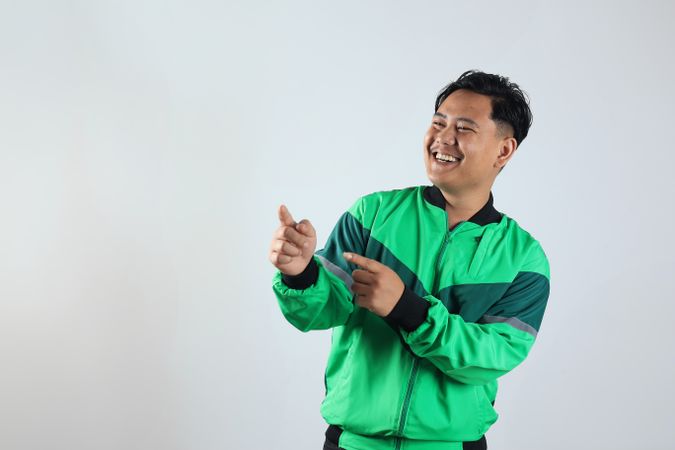 Asian Gojek Grab Online Driver with Unifrom Jacket Pointing at Copy Space