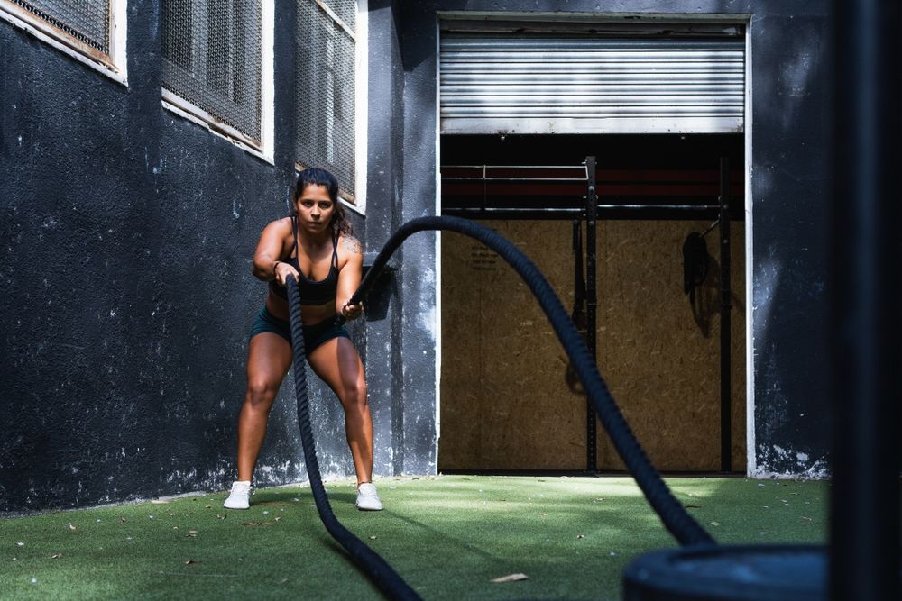 Strong Hispanic woman exercising with battle ropes