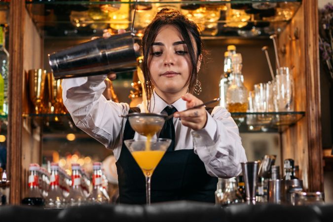 Female bartender preparing a cocktail in a traditional cocktail bar