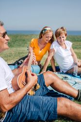Family on outdoor picnic with ukulele, vertical