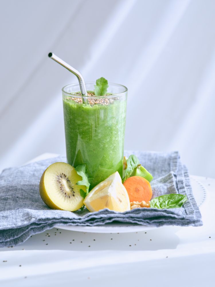 Green smoothie near cut fruits