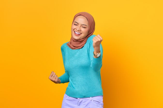 Thrilled Muslim woman celebrating with eyes closed