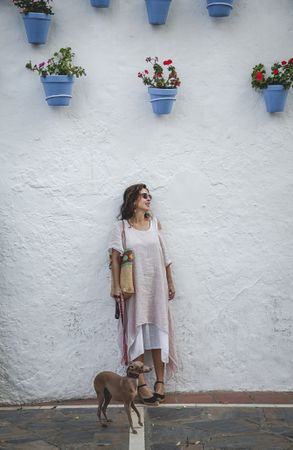 Cheerful female standing with dog near street wall