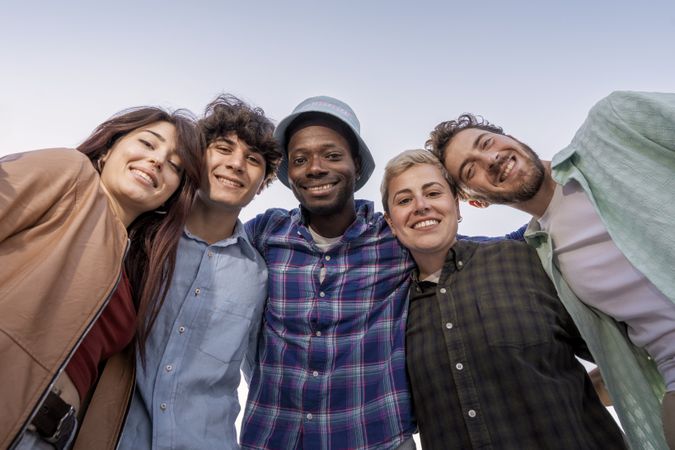 Multiracial young friends smiling and bonding outdoors in sunny day