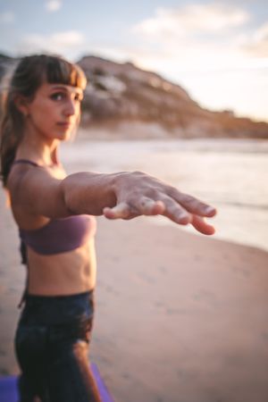 Fit woman stretching her arms at the beach, with focus on hand