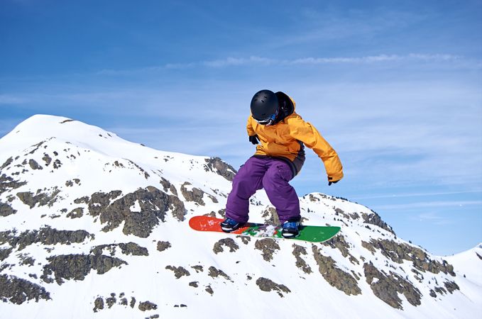 Unrecognizable snowboarder jumping on slope