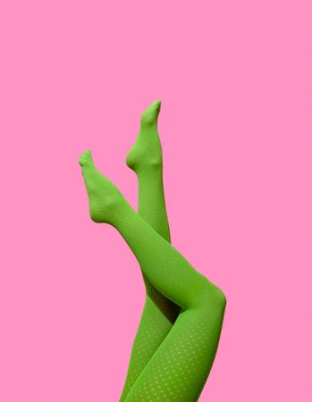 Female legs in green tights against a pink wall