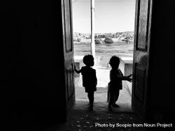Grayscale photo of two children standing at the door in Aswan, Egypt 5nKKm4