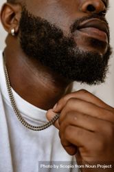 Cropped image of Black man with a beard wearing light shirt and silver necklace 5rKZ34