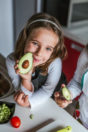 Little girl showing cut avocado