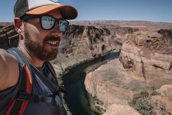 Smiling man in sunglasses taking selfie in mountains