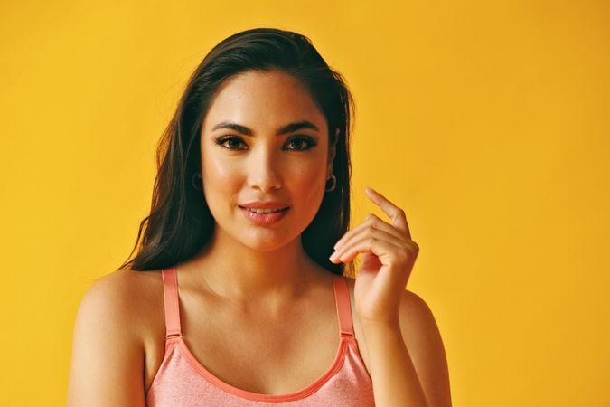 Headshot of confident Hispanic woman looking at camera with hand up to side of her face