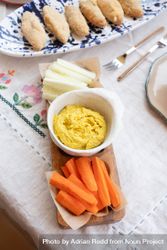 Fresh carrots and cucumber with hummus dip set on casual table be21N0