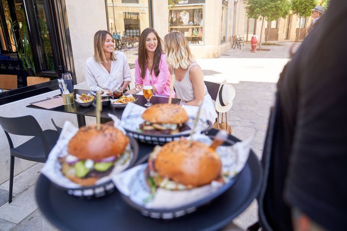 Waiter bringing order to women in street cafe