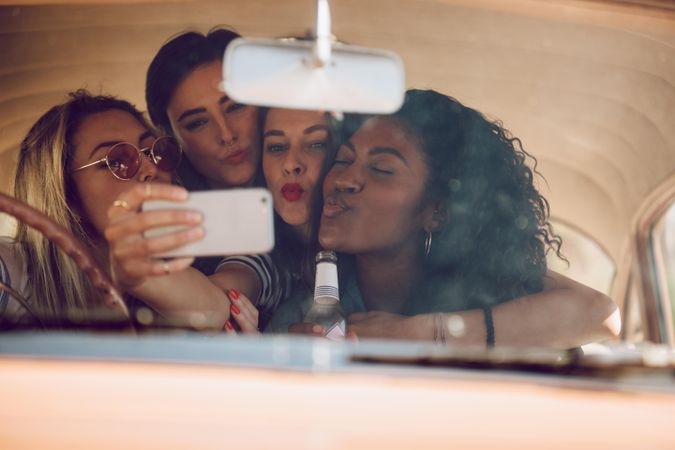 Cheerful female friends taking selfie in a car