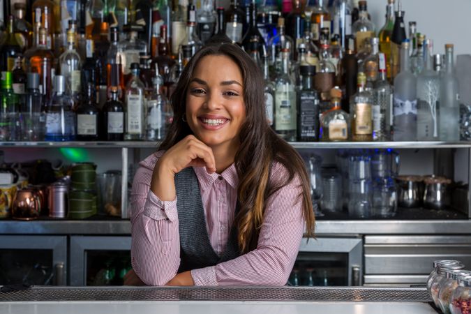Smiling bartender with chin on hand at the bar