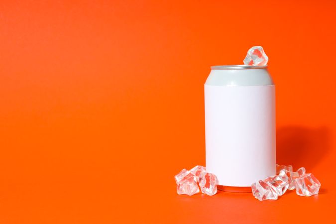 Blank can with ice cubes on orange background