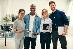 Multi-ethnic group of colleagues standing in line with their arms around each other
