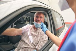 Crop physician with cotton swab against smiling patient in autom