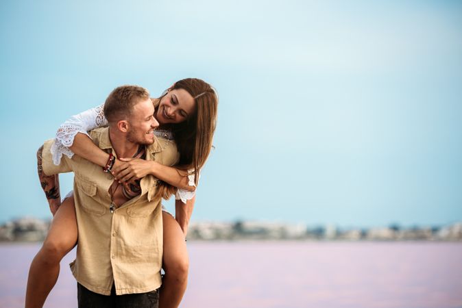 adorable couple giving a piggyback ride on an amazing beach of pink water