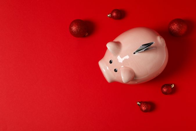 Piggy bank, cash and balls on red background, space for text