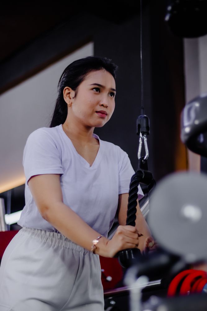 Concentrated athletic woman working triceps with rope pushdowns.