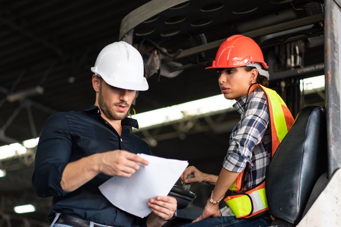 Warehouse supervisor and female forklift operator reviewing documents