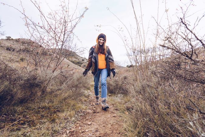 Hiker with backpack walking along pathway in autumn forest