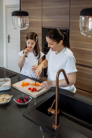 Mother preparing snack for school while her daughter eats carrot
