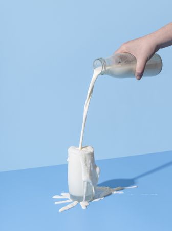 Pouring milk into the glass on a blue background