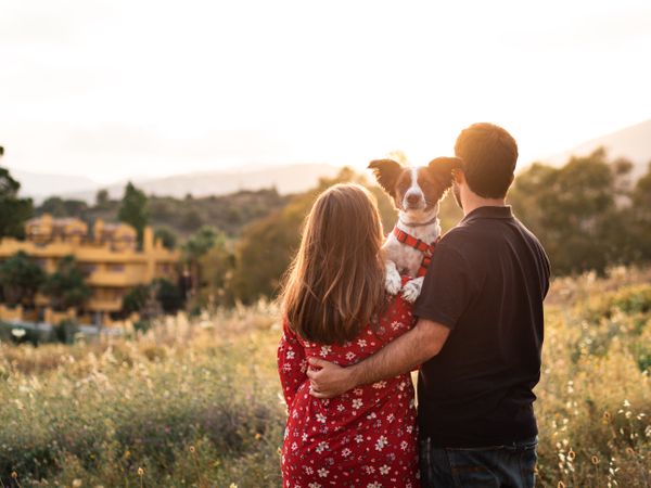 Happy couple with friendly cute dog outdoors