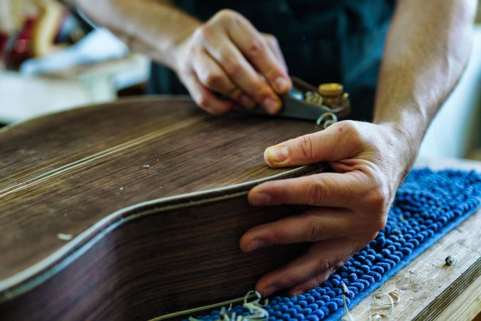 Close up of luthier’s hands working on a guitar