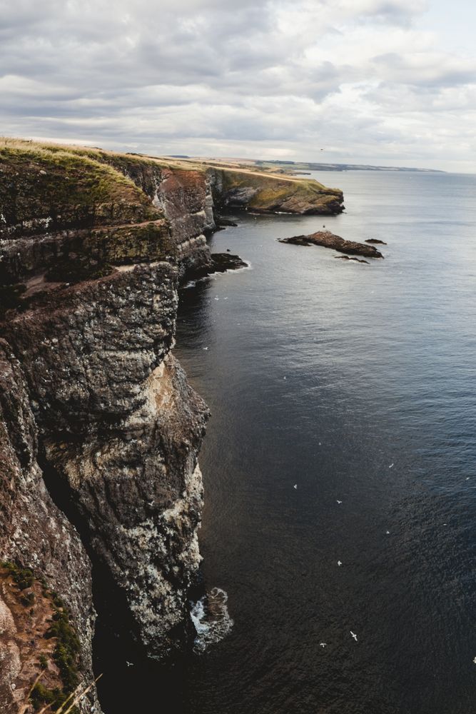 Rocky coast among tranquil ocean water in sunny day