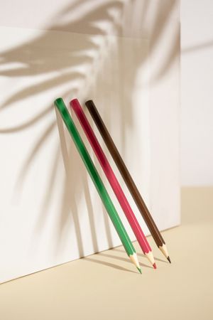 Three pencils standing against the wall with shadow