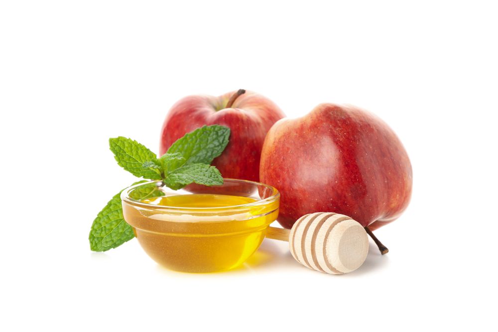 Side view of two apples, leaves and a pot of honey