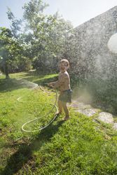 Little child having fun with garden hose and water