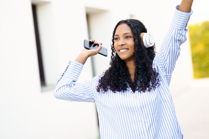 A Joyful Young Woman Is Enjoying Music While Outdoors, Wearing Headphones to Listen