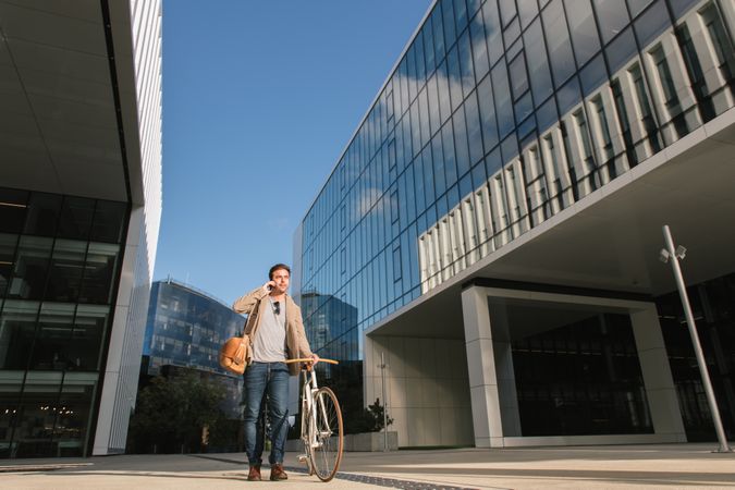 Man phoning while standing against modern building in downtown