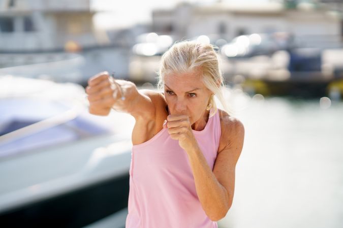 Mature woman practicing boxing on a coastal pier