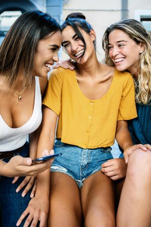 Vertical shot of three female friends laughing together