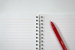 Open notebook and red pen isolated on blank background