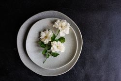 Top view of minimalistic table setting with flowers on grey plate with copy space