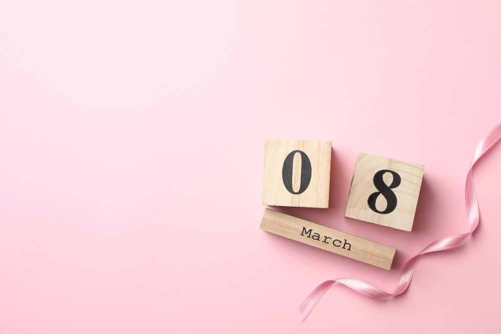 Wooden calendar and ribbon on pink background, space for text