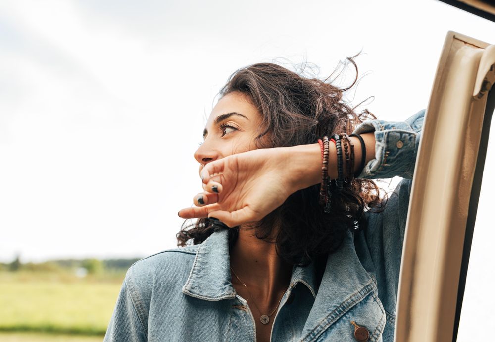 Woman looking away with arm up on car door