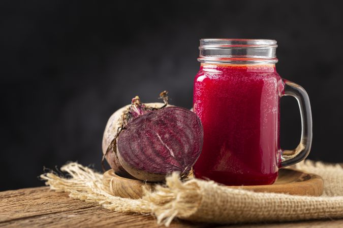 Red beet juice in a glass cup on the wooden table.