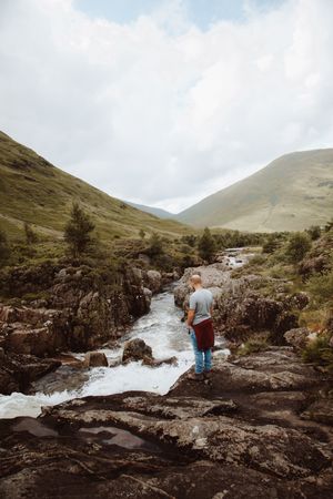 Man standing on bank of mountain river