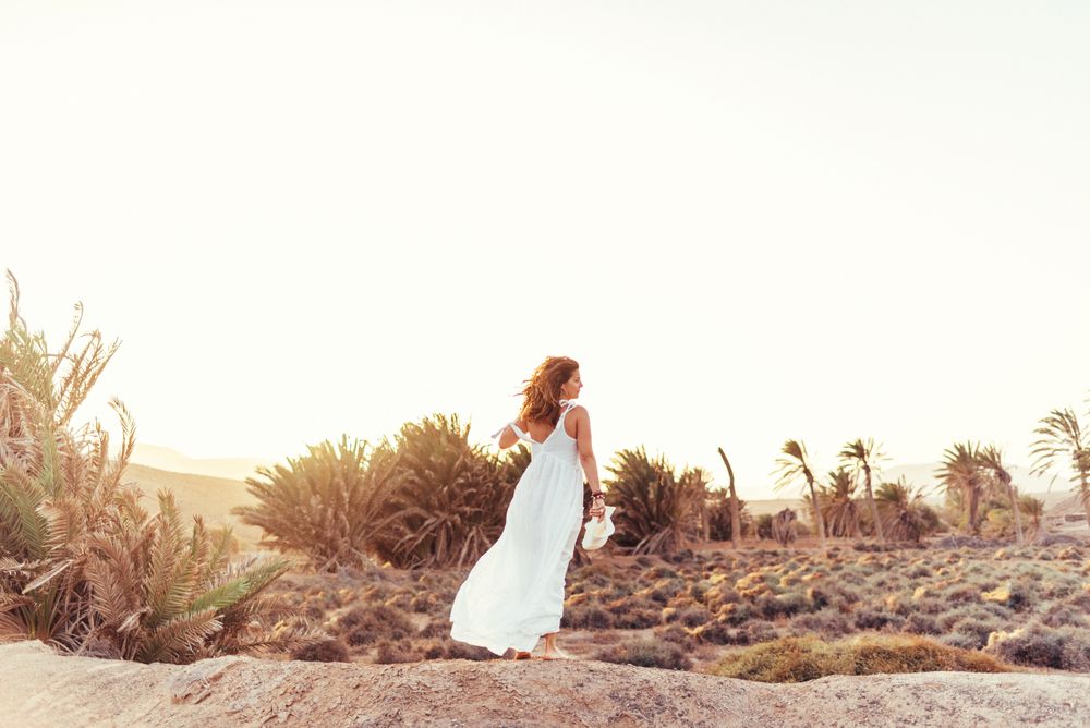 Woman in white dress in dry field in sunlight