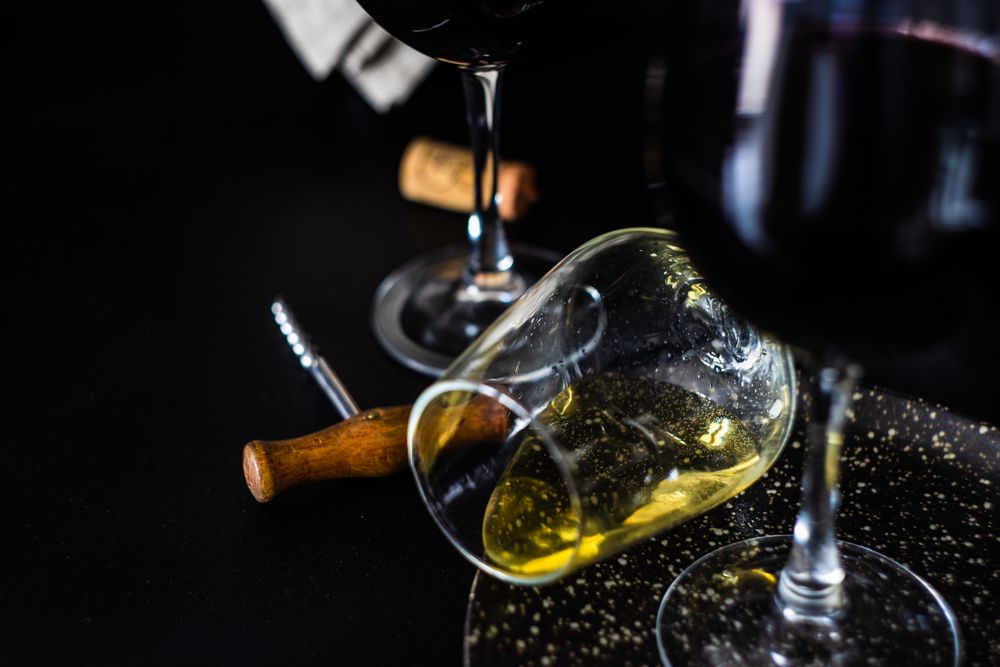 Fallen wine glass on counter with opener and cork