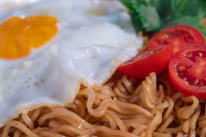 A plate of noodles with an egg and tomato on top