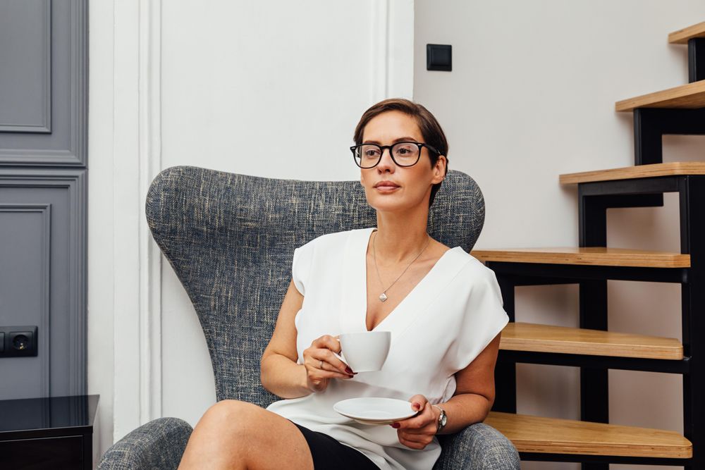 Woman sitting near stairs with a coffee